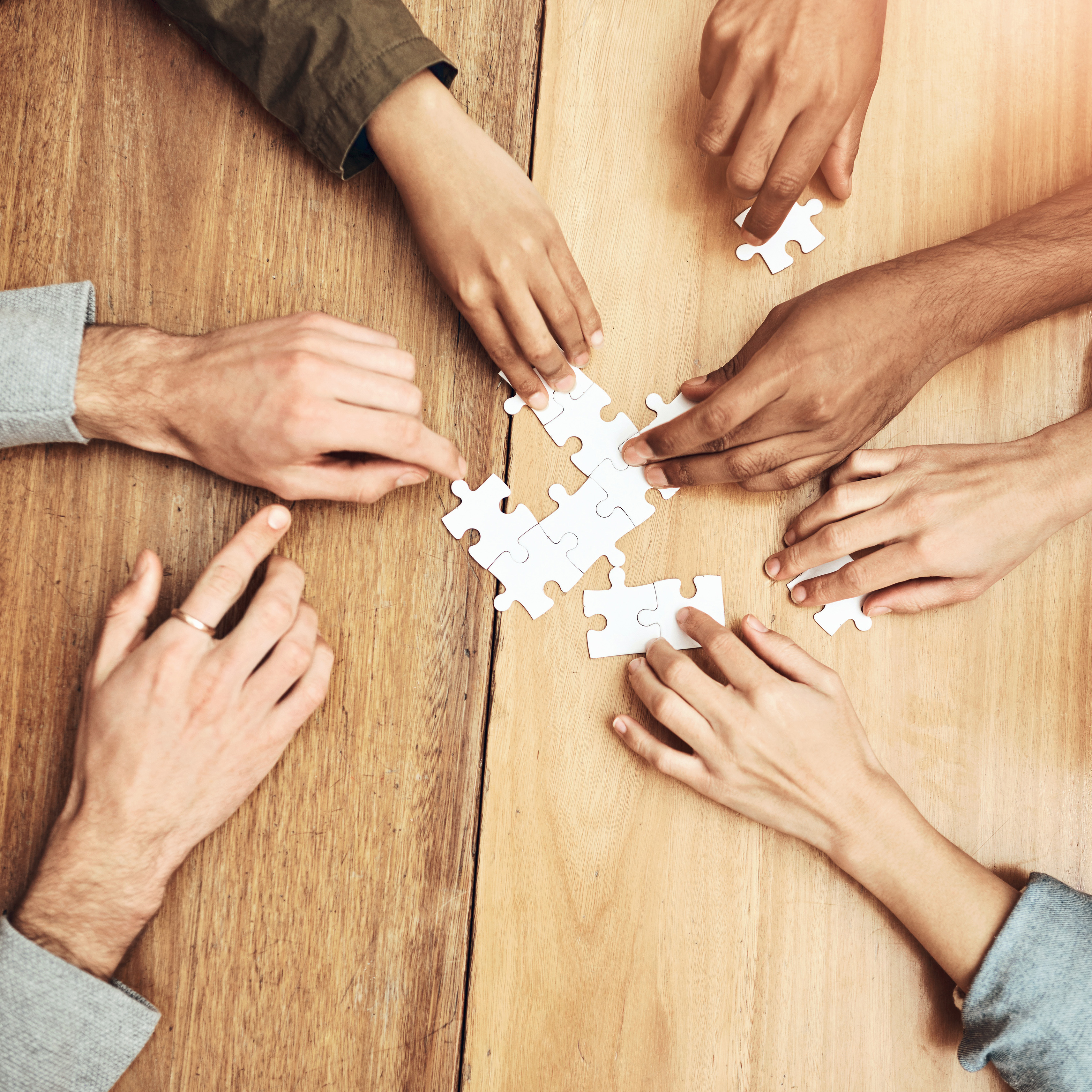 viele Hände die Puzzle-Teile halten