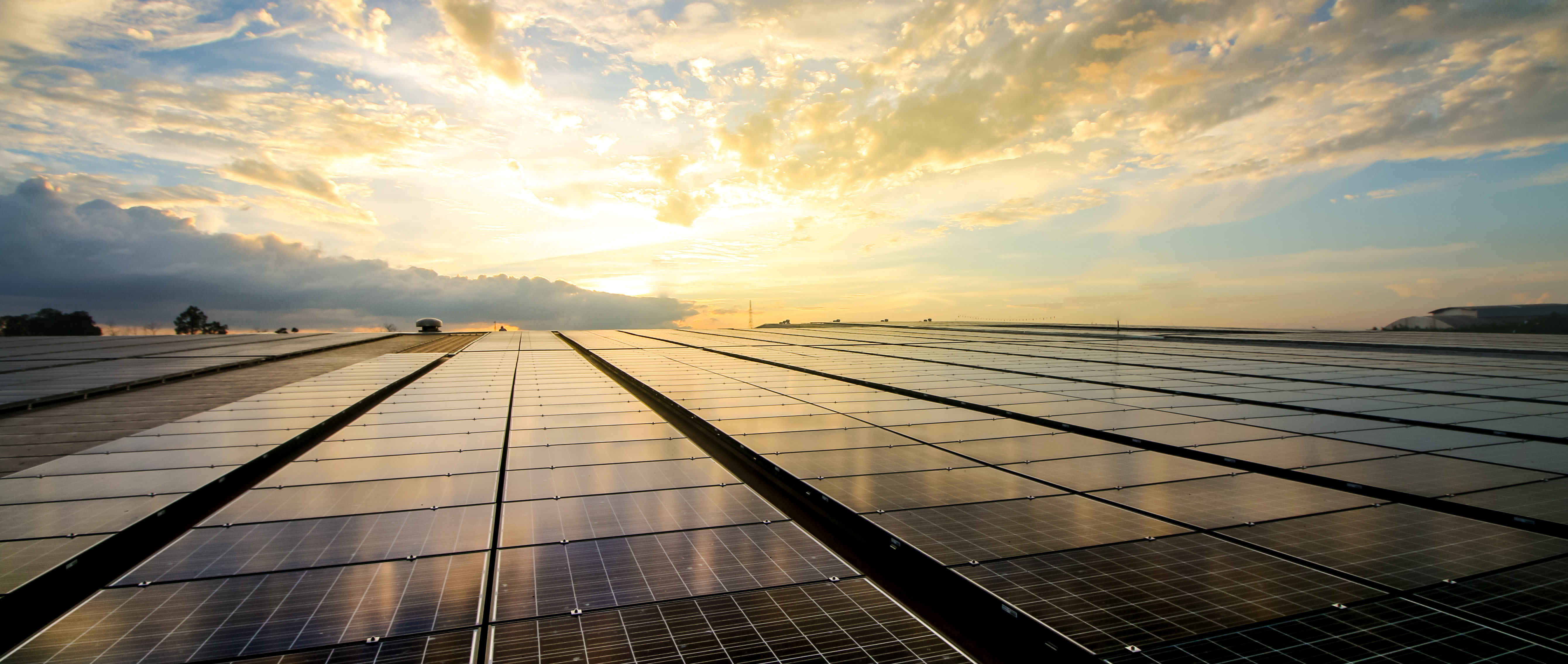HEaderbild Solarpanels on a rooftop with a sunset in the Background
